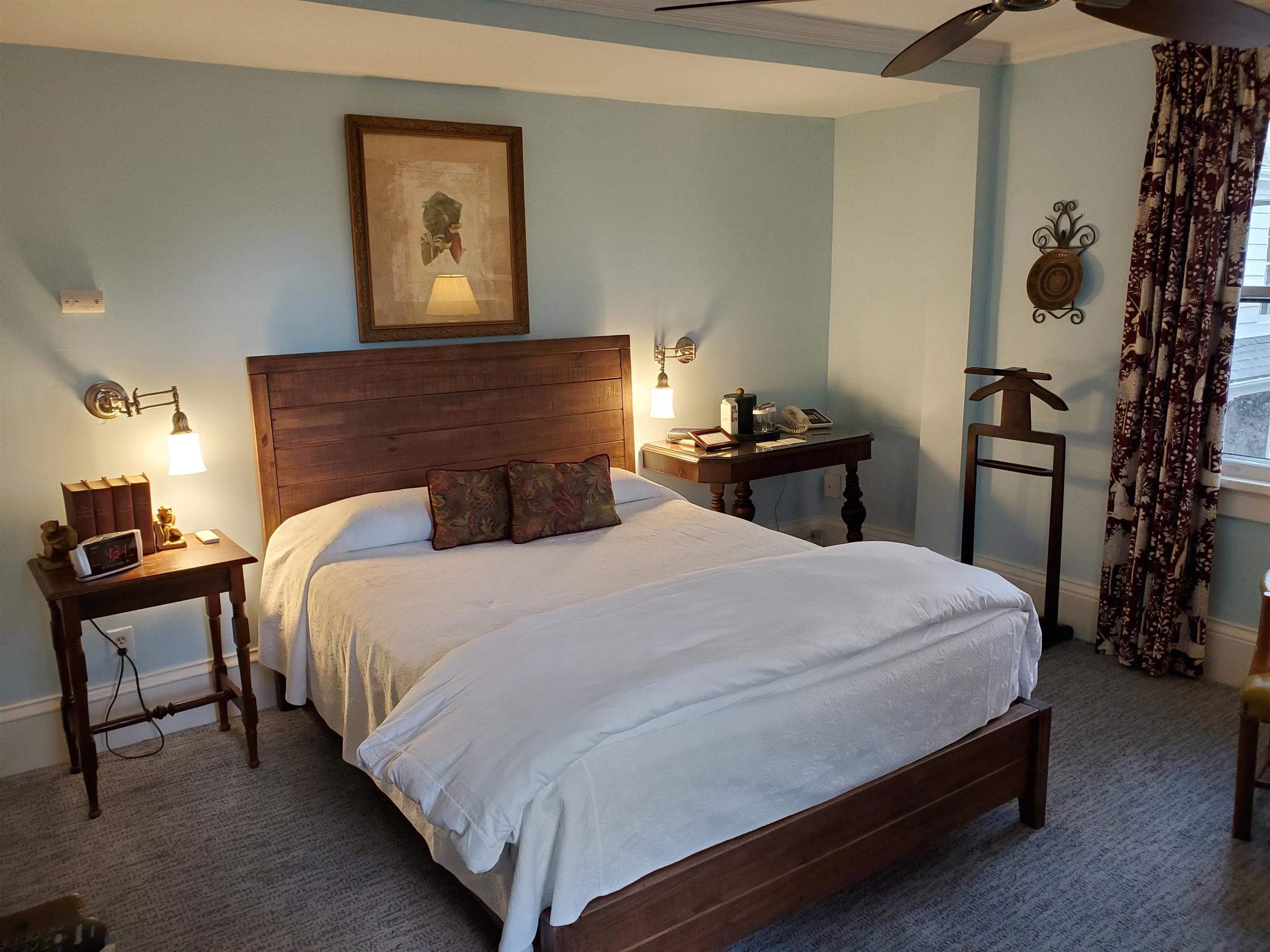 A hotel room with a large bed, wooden furniture, and a window.