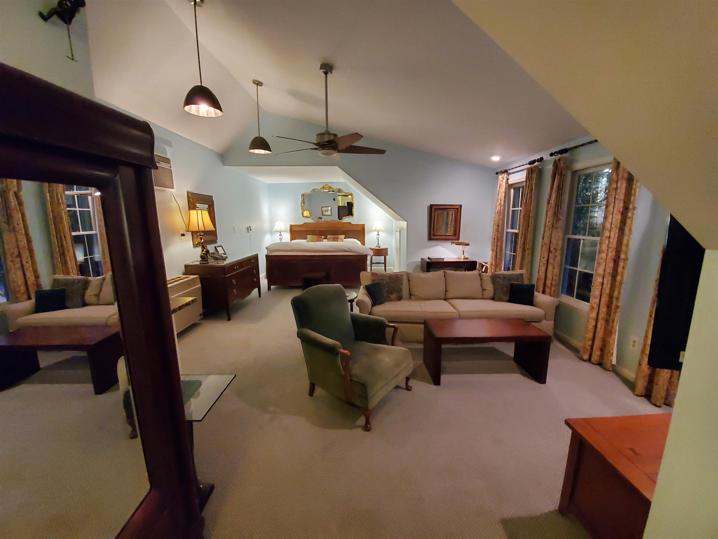 A wide view of a spacious suite with a living area and a bedroom in the background.