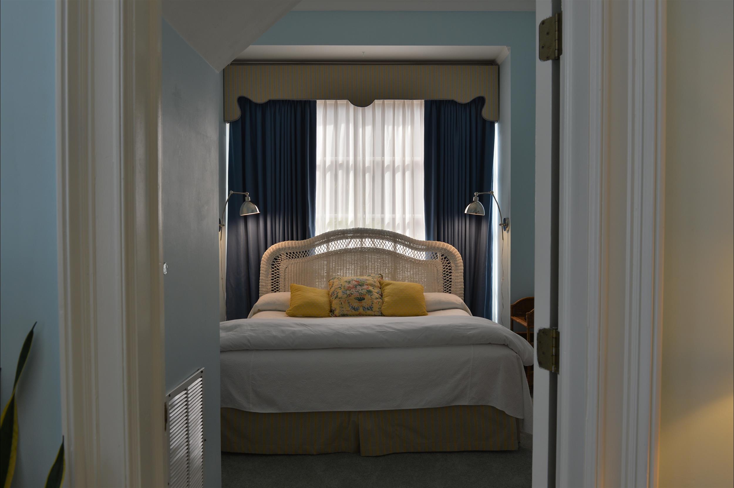 A bedroom with a bed, window, and curtains visible through a doorway.